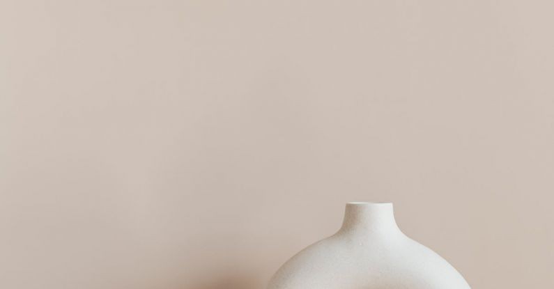 Co-Living Spaces - White ceramic vase in creative shape of ring placed on white marble stand against beige wall as home decoration element or art object