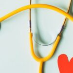 Personalized Medicine - Medical stethoscope with red paper heart on white surface