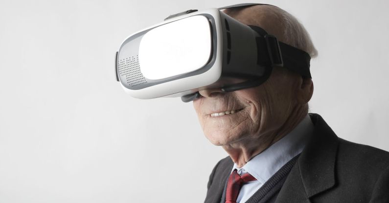 Reality Shows - Smiling elderly gentleman wearing classy suit experiencing virtual reality while using modern headset on white background