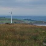 Sustainable Agriculture - Anonymous female travelers looking at windmill in meadow in countryside