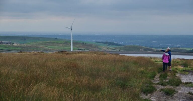 Sustainable Agriculture - Anonymous female travelers looking at windmill in meadow in countryside