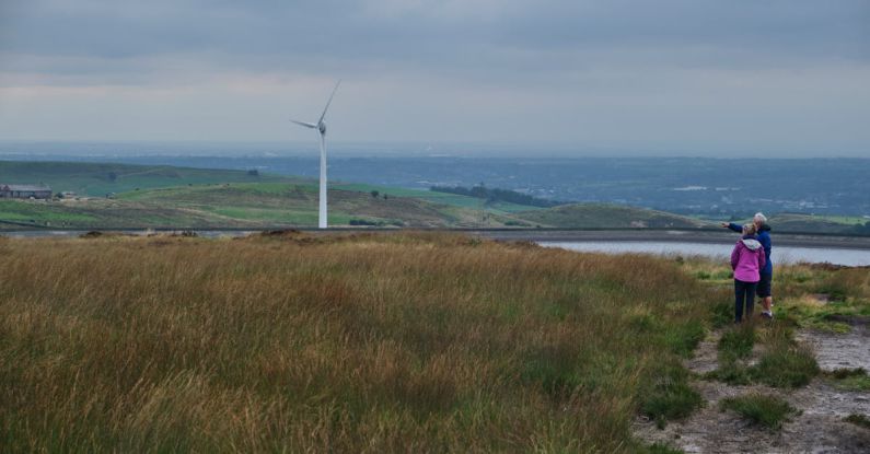 Sustainable Agriculture - Anonymous female travelers looking at windmill in meadow in countryside