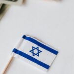 Financial Independence - From above set of miniature toothpick flags of USA and Israel placed on white table with dollar banknotes