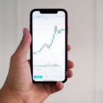 Day Trading - Person Holding a Phone with Data on the Screen